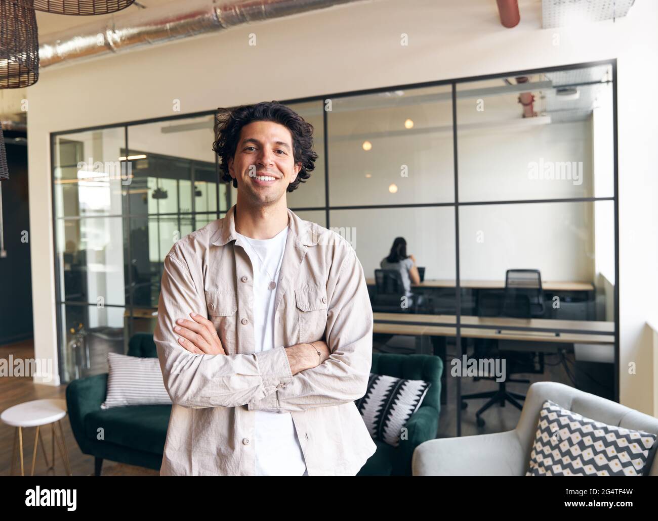 Porträt eines lässig gekleideten jungen Mannes, der in einem modernen Großraumbüro seines neuen Unternehmens steht Stockfoto