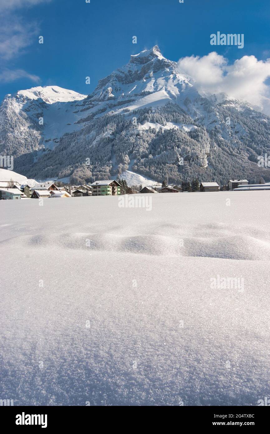Eine Landschaft eines sonnenbeschienenen schneebedeckten Feldes mit Bergkulisse bei Engelberg, Kanton Obwalden, Zentralschweiz Stockfoto