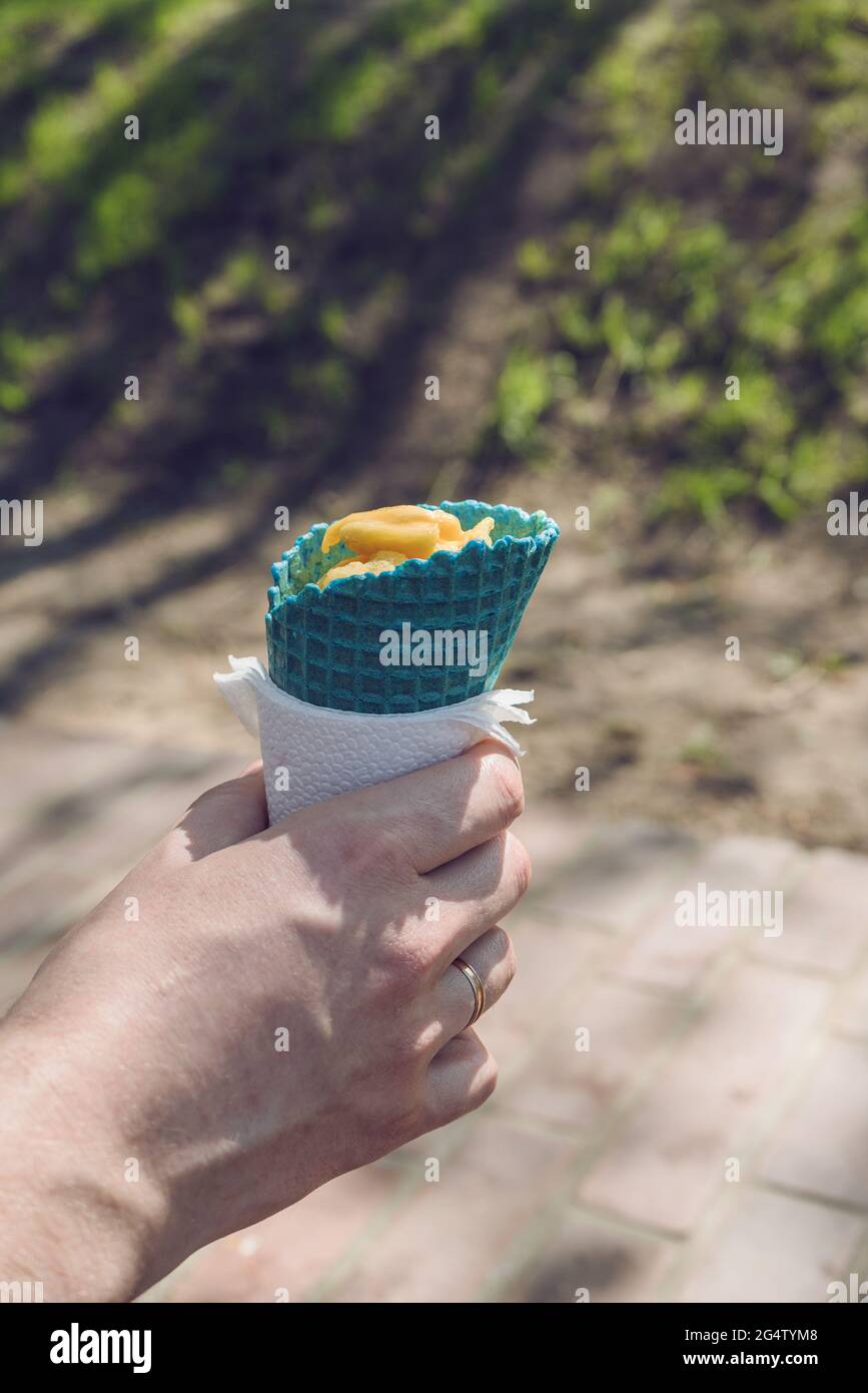 Mann, der an sonnigen Tagen farbige Eiskegel mit Mango-Eis im Inneren hält Stockfoto