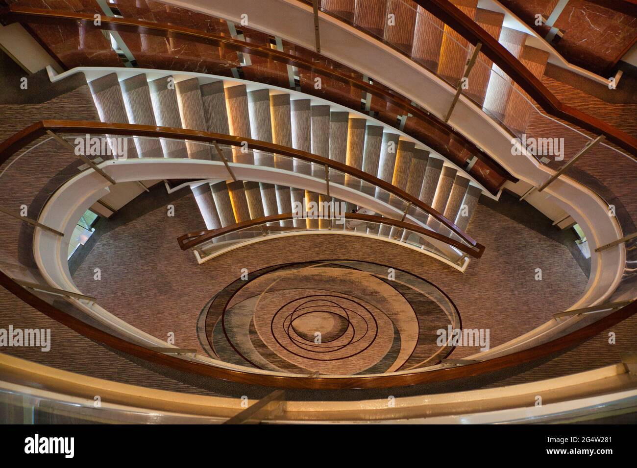 Blick hinunter durch die Mitte einer ovalen Treppe auf einem Kreuzschiff Stockfoto