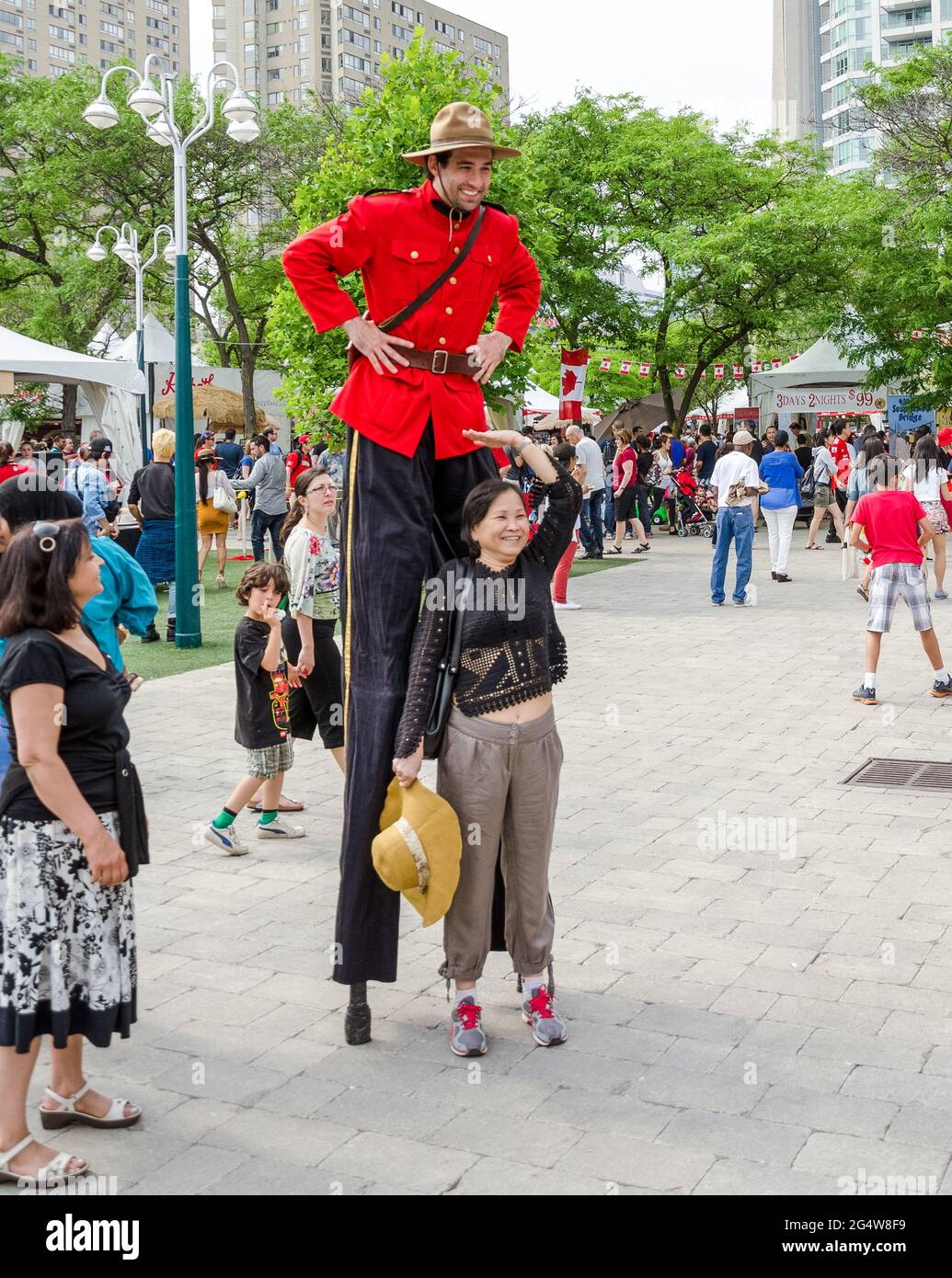 Kanadische mountie auf einem Canada Day Urlaub auf Stelzen posiert mit einer lächelnden Frau für Touristenfotos. Stockfoto