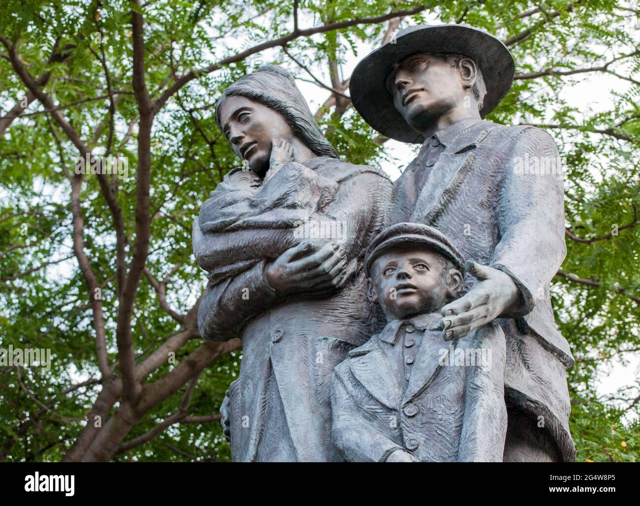 Das Denkmal für italienisch-kanadische Einwanderer:EINE Statue einer vierköpfigen Familie sticht vor einem Hintergrund aus Baum und Himmel hervor. Die Familie besteht aus einem mot Stockfoto