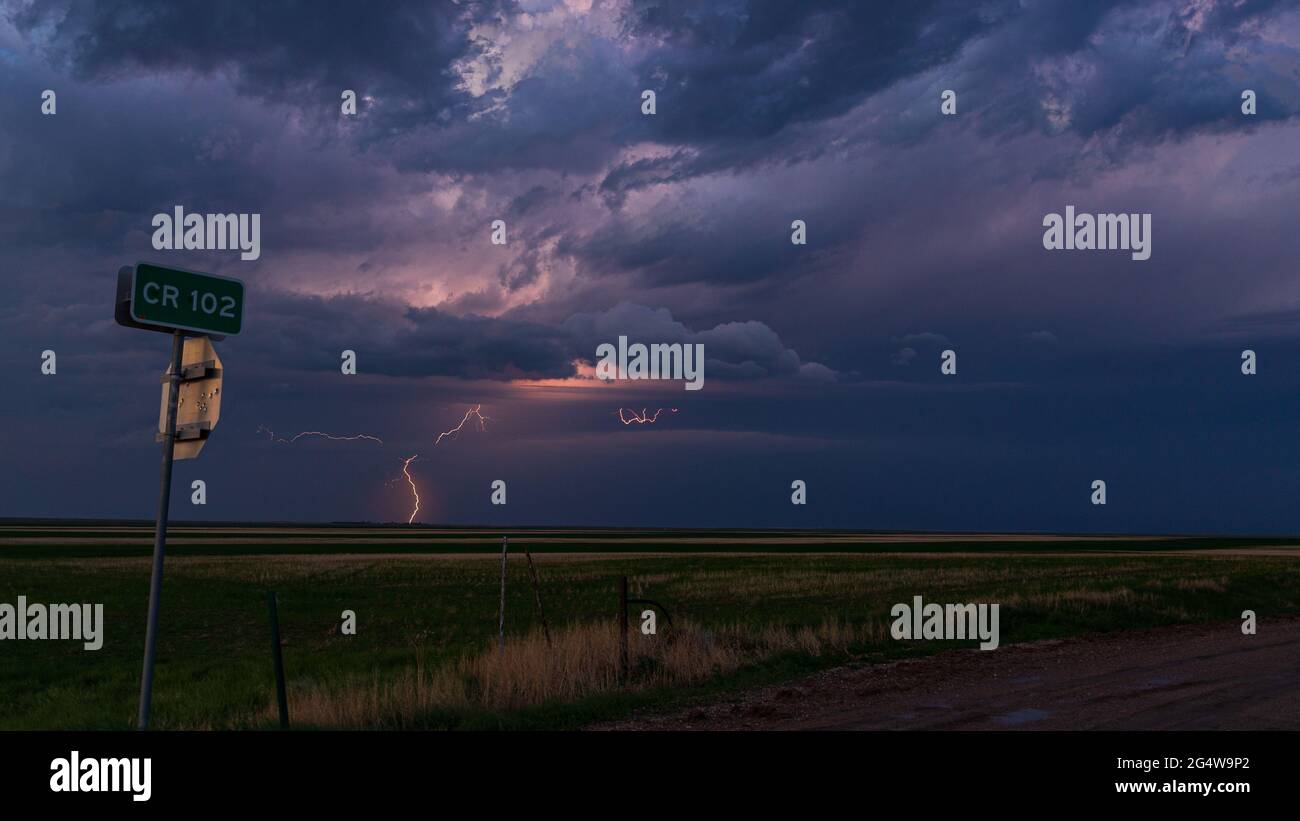 Blitzschlag schlägt in der Ferne ein und beleuchtet einen dunklen und bedrohlichen Himmel, während ein Gewitter durch den Osten Colorados zieht Stockfoto