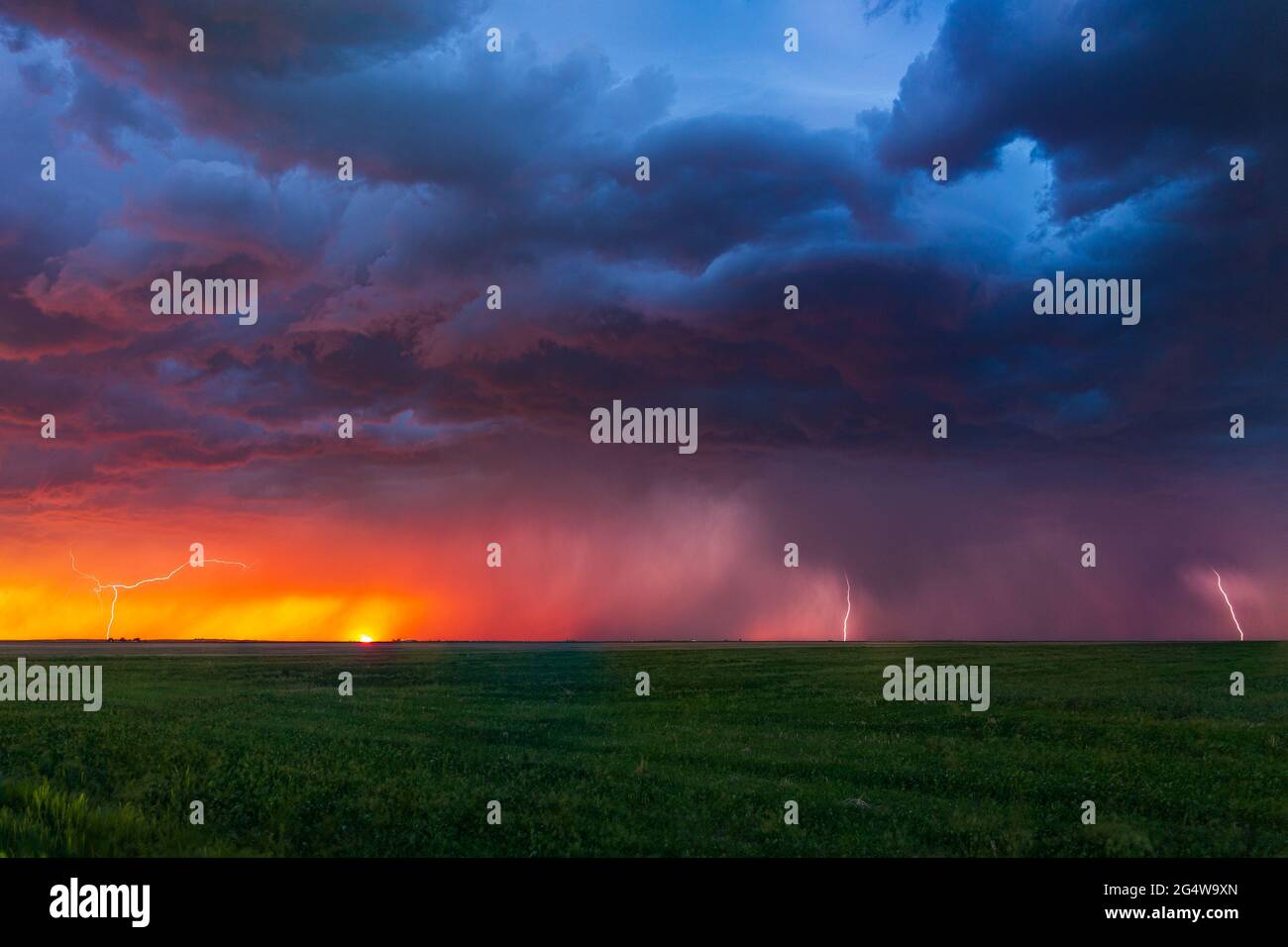 Bei Sonnenuntergang schlagen Blitze entlang der Grenze von Wyoming/Colorado. Die letzten Reste der Sonne können am Horizont untergehen gesehen werden Stockfoto