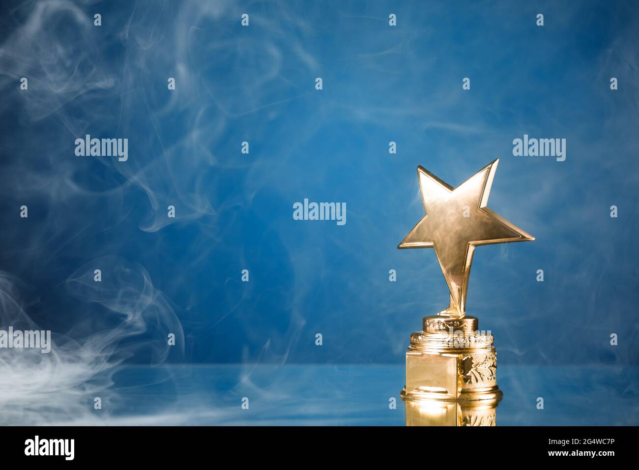 Gold Star Trophäe in Rauch, blauer Hintergrund Stockfoto