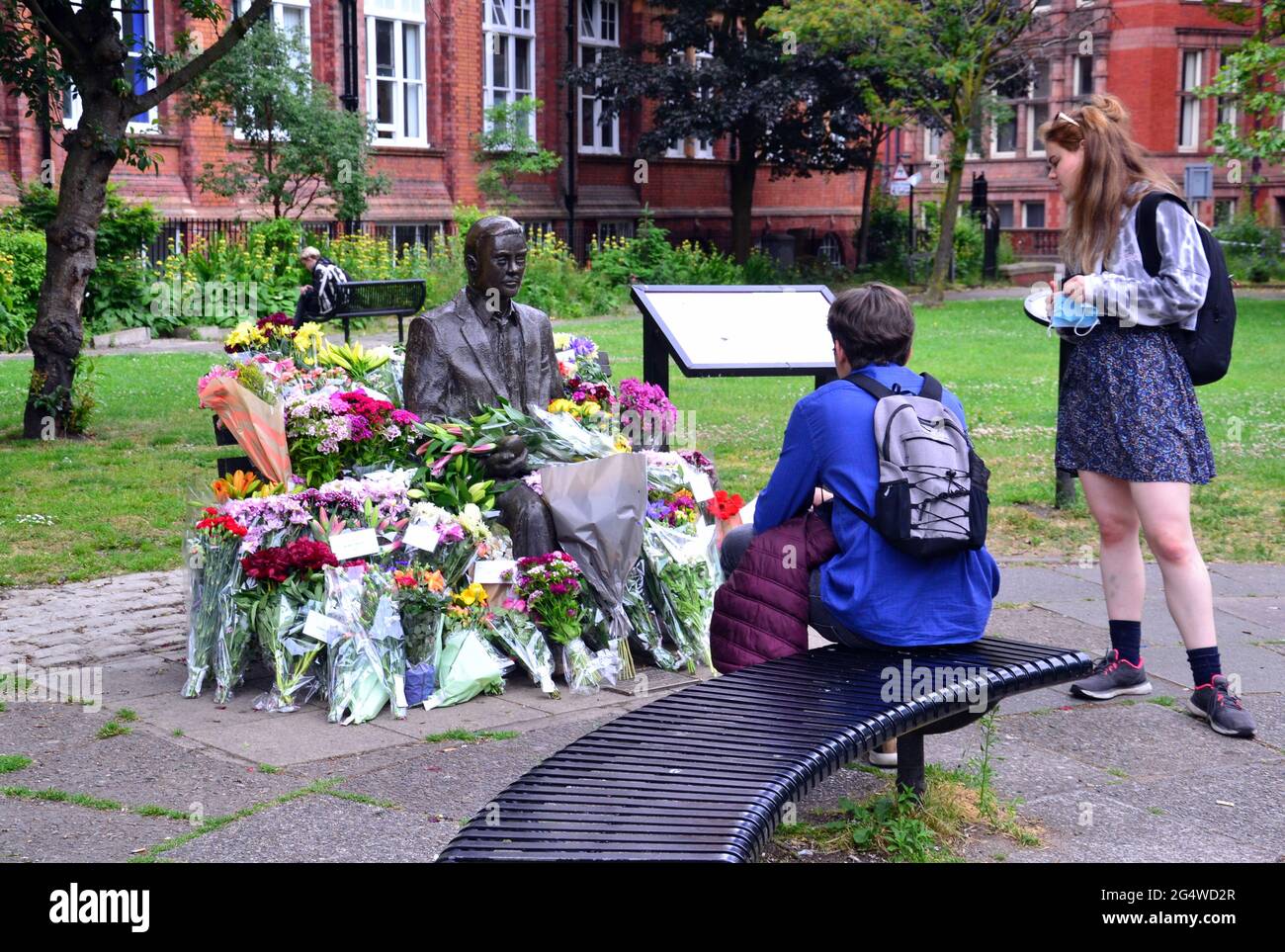 Blumen umgeben die Alan Turing Statue und das Denkmal, Sackville Gardens, Manchester, England, Großbritannien, Vereinigtes Königreich, am 23. Juni 2021, dem Jahrestag von Turing's Geburtstag. Alan Mathison Turing OBE war ein englischer Mathematiker, Informatiker, Logiker und Kryptanalyst. Im 2. Weltkrieg leitete er ein Team, das dafür verantwortlich war, deutsche Cipher der Enigma-Maschine zu brechen. Turing hatte damals Einfluss auf die Entwicklung der Informatik an der University of Manchester. Stockfoto