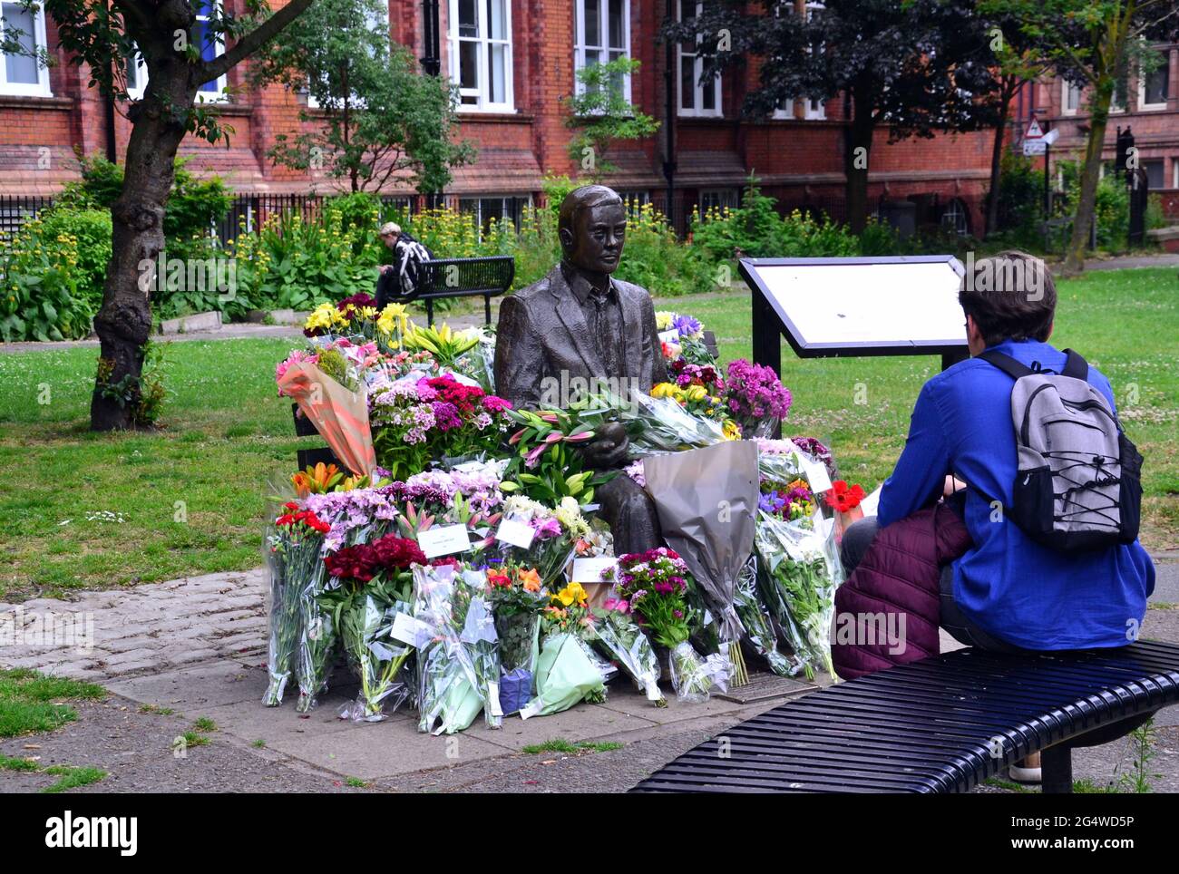 Blumen umgeben die Alan Turing Statue und das Denkmal, Sackville Gardens, Manchester, England, Großbritannien, Vereinigtes Königreich, am 23. Juni 2021, dem Jahrestag von Turing's Geburtstag. Alan Mathison Turing OBE war ein englischer Mathematiker, Informatiker, Logiker und Kryptanalyst. Im 2. Weltkrieg leitete er ein Team, das dafür verantwortlich war, deutsche Cipher der Enigma-Maschine zu brechen. Turing hatte damals Einfluss auf die Entwicklung der Informatik an der University of Manchester. Stockfoto