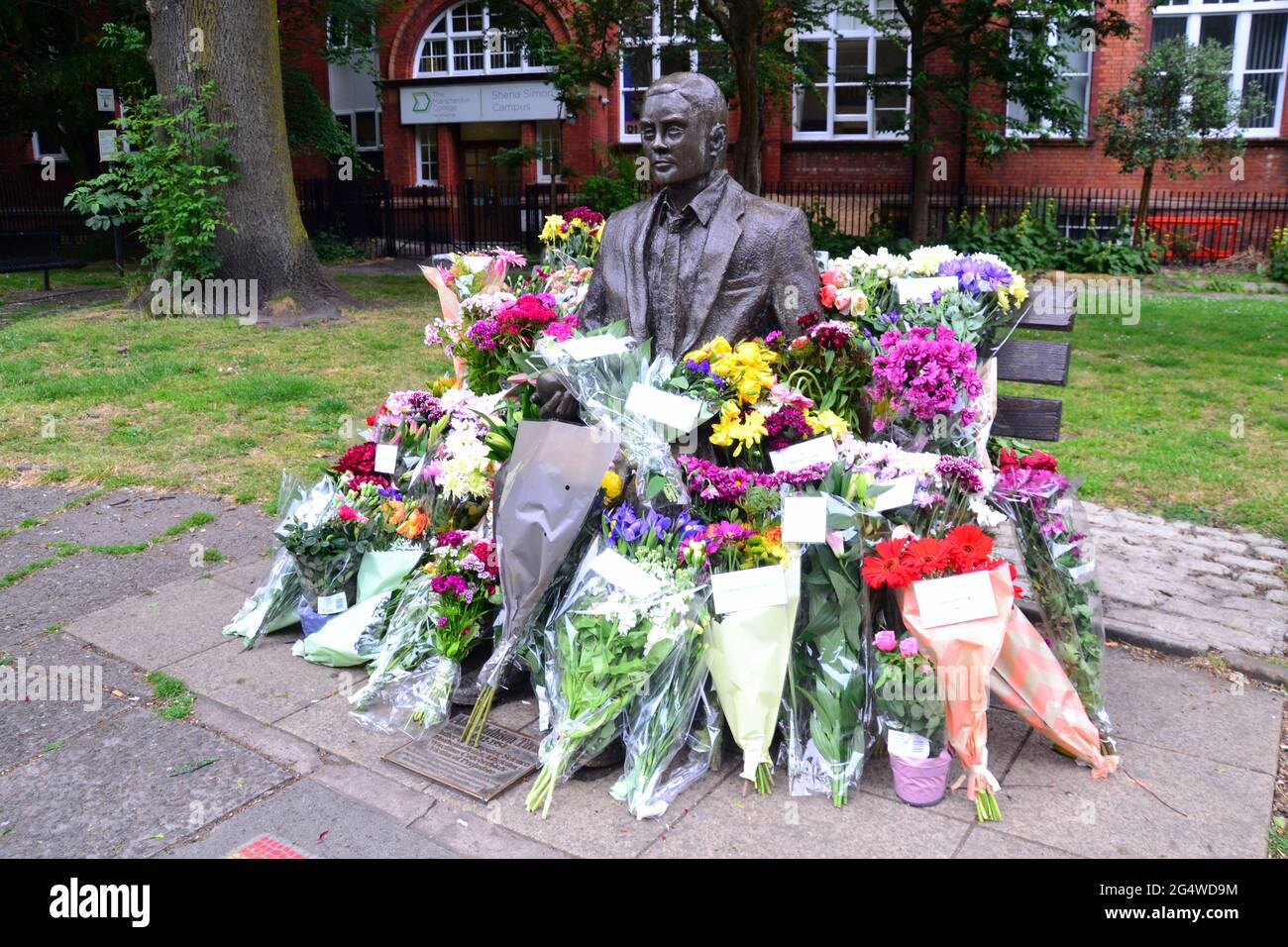 Blumen umgeben die Alan Turing Statue und das Denkmal, Sackville Gardens, Manchester, England, Großbritannien, Vereinigtes Königreich, am 23. Juni 2021, dem Jahrestag von Turing's Geburtstag. Alan Mathison Turing OBE war ein englischer Mathematiker, Informatiker, Logiker und Kryptanalyst. Im 2. Weltkrieg leitete er ein Team, das dafür verantwortlich war, deutsche Cipher der Enigma-Maschine zu brechen. Turing hatte damals Einfluss auf die Entwicklung der Informatik an der University of Manchester. Stockfoto