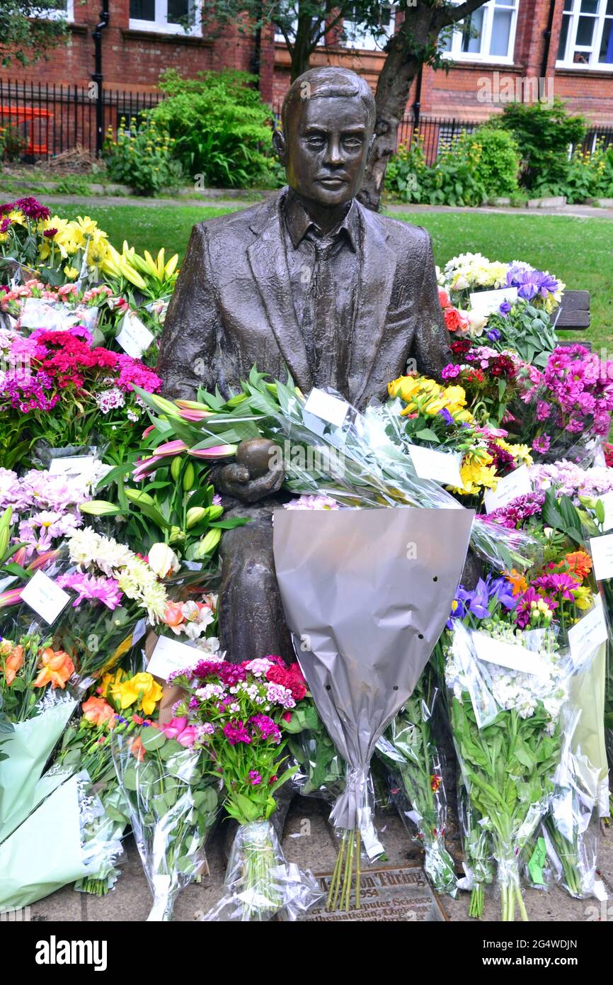 Blumen umgeben die Alan Turing Statue und das Denkmal, Sackville Gardens, Manchester, England, Großbritannien, Vereinigtes Königreich, am 23. Juni 2021, dem Jahrestag von Turing's Geburtstag. Alan Mathison Turing OBE war ein englischer Mathematiker, Informatiker, Logiker und Kryptanalyst. Im 2. Weltkrieg leitete er ein Team, das dafür verantwortlich war, deutsche Cipher der Enigma-Maschine zu brechen. Turing hatte damals Einfluss auf die Entwicklung der Informatik an der University of Manchester. Stockfoto