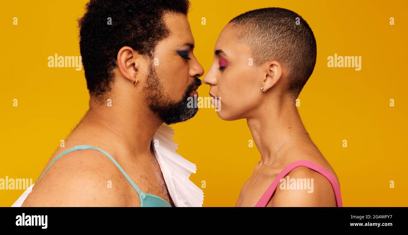 Profilansicht eines Männchens und einer Frau, die Make-up tragen, mit ihrem Gesicht nahe beieinander. Konzeptuelles Bild von Nichtkonformität Stockfoto