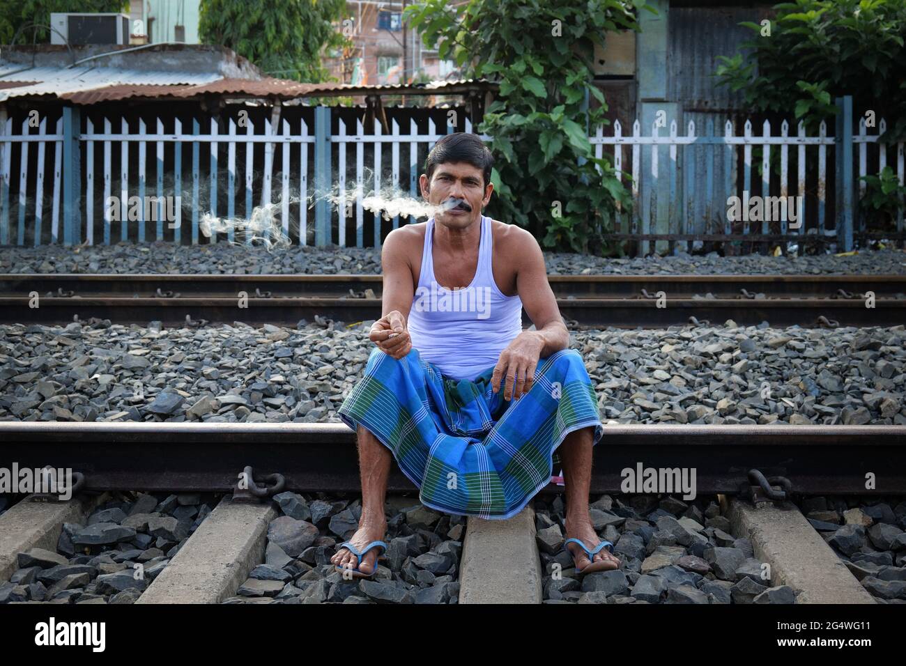 Kalkutta, Indien. Juni 2021. Harulal Mondol, 55 Jahre alt, ein Maurer von Beruf, sitzt auf einer Eisenbahnstrecke, während er raucht, da die örtlichen Zugverbindungen aufgrund der staatlichen Sperrbeschränkungen nicht wieder aufgenommen wurden. (Foto von Dipayan Bose/SOPA Images/Sipa USA) Quelle: SIPA USA/Alamy Live News Stockfoto