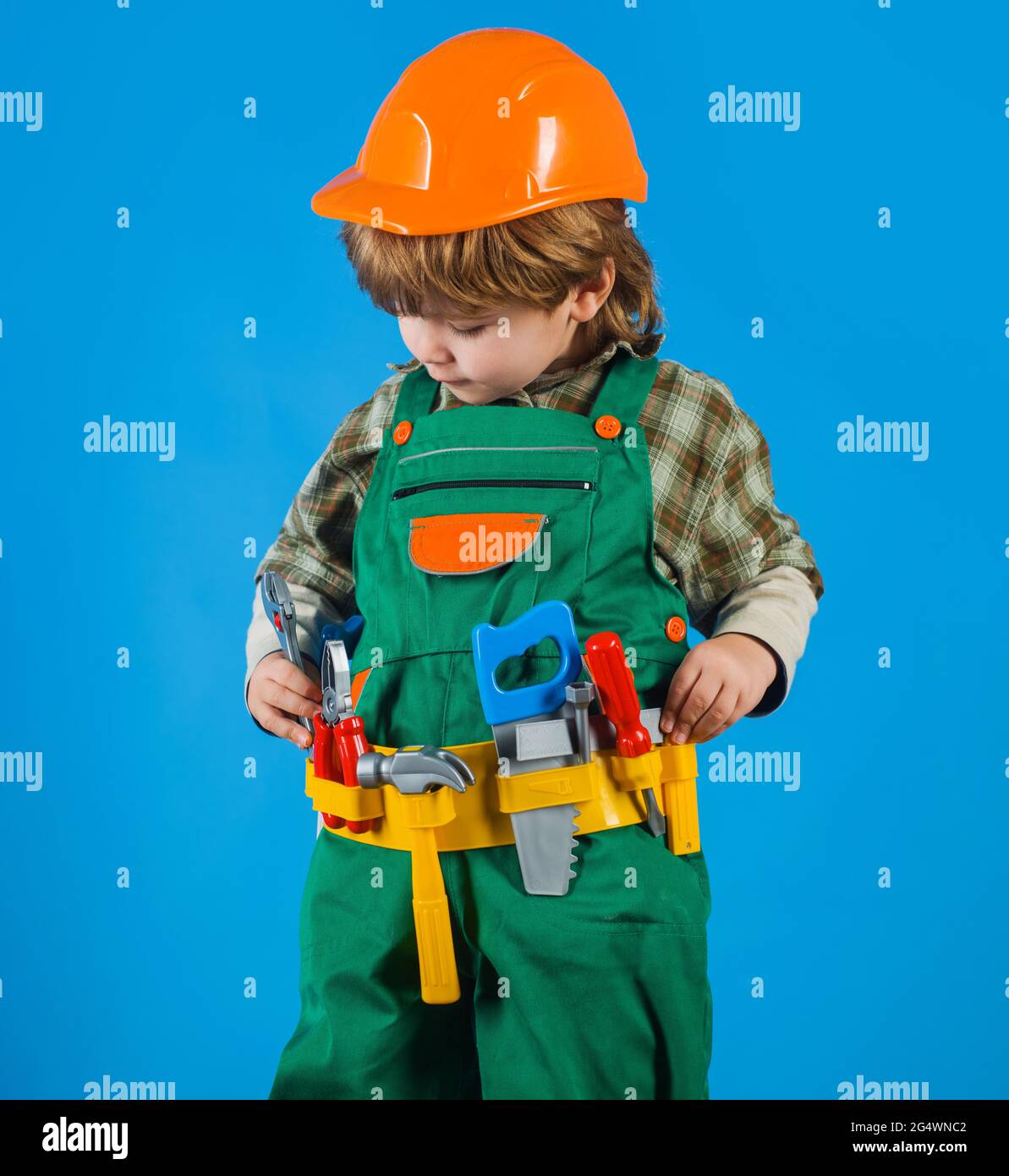 Kleiner Junge in Bauherren Uniform mit Werkzeuggürtel. Werkzeuge für das Bauen. Kinderreparaturmann. Kinderspiel. Stockfoto