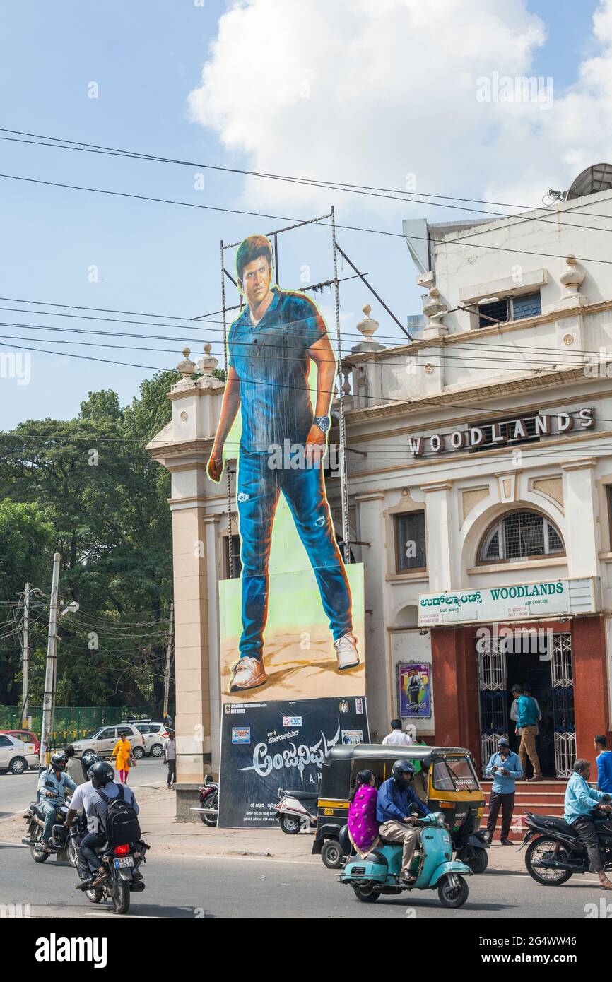 Viel Verkehr, der sich vor dem Woodlands-Kino herum bewegt, mit großen Werbetafeln, auf denen die neueste Filmveröffentlichung, Mysore, Karnataka, Indien, angezeigt wird Stockfoto