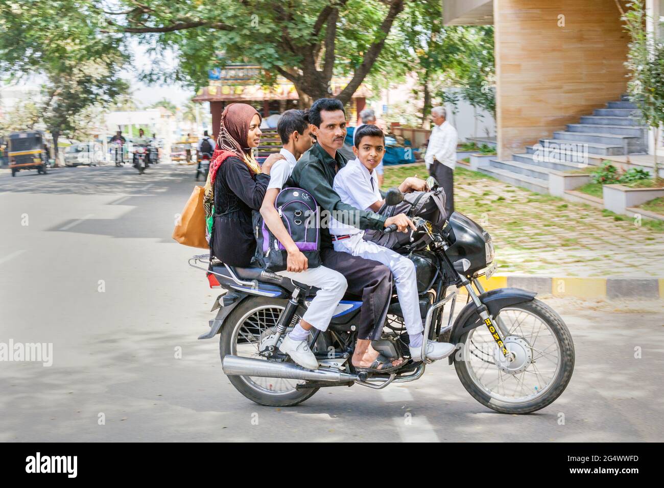 Indische muslimische vierköpfige Familie, die auf einem Motorrad ohne Sturzhelme fährt, Mysore, Karnataka, Indien (aufgenommen mit „Schwenken“-Fototechnik) Stockfoto