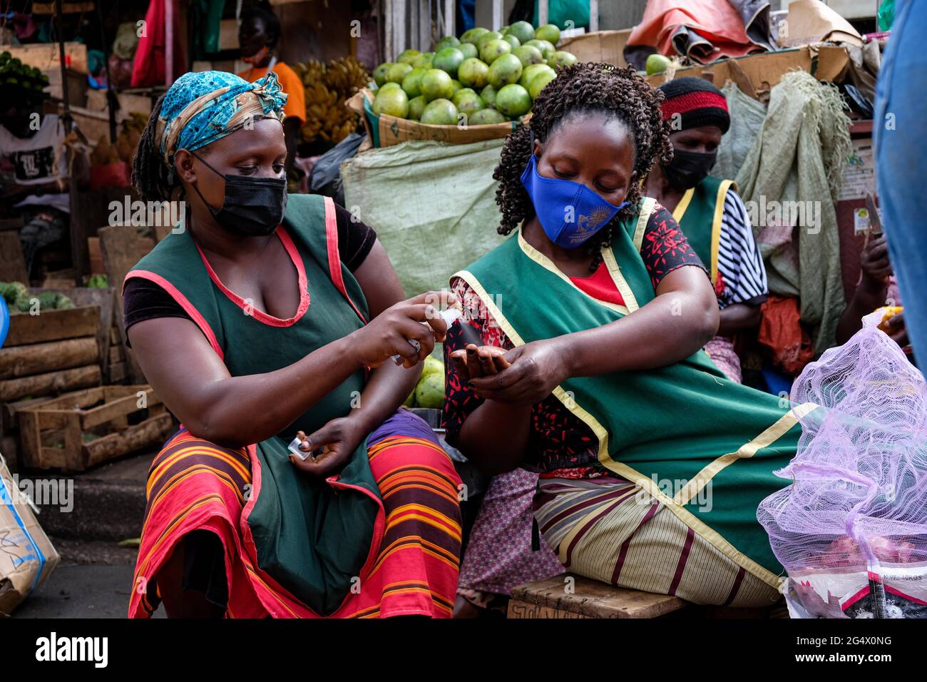 Kampala, Uganda. Juni 2021. Ein Anbieter hilft einem anderen Anbieter, ihre Hände am 23. Juni 2021 auf einem Markt in Kampala, Uganda, zu desinfizieren. Eine virulente zweite Welle von COVID-19 zerstört das Land mit einer positiven Rate von 17.1 Prozent weiter. Quelle: Hascharah Nalwadda/Xinhua/Alamy Live News Stockfoto