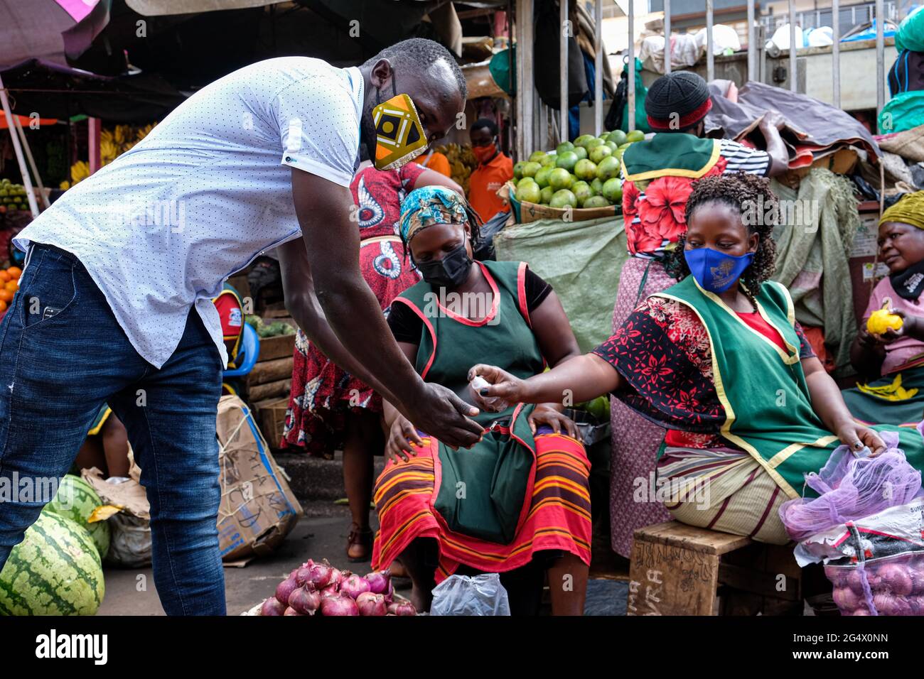 Kampala, Uganda. Juni 2021. Am 23. Juni 2021 desinfiziert ein Anbieter die Hände eines Kunden auf einem Markt in Kampala, Uganda. Eine virulente zweite Welle von COVID-19 zerstört das Land mit einer positiven Rate von 17.1 Prozent weiter. Quelle: Hascharah Nalwadda/Xinhua/Alamy Live News Stockfoto