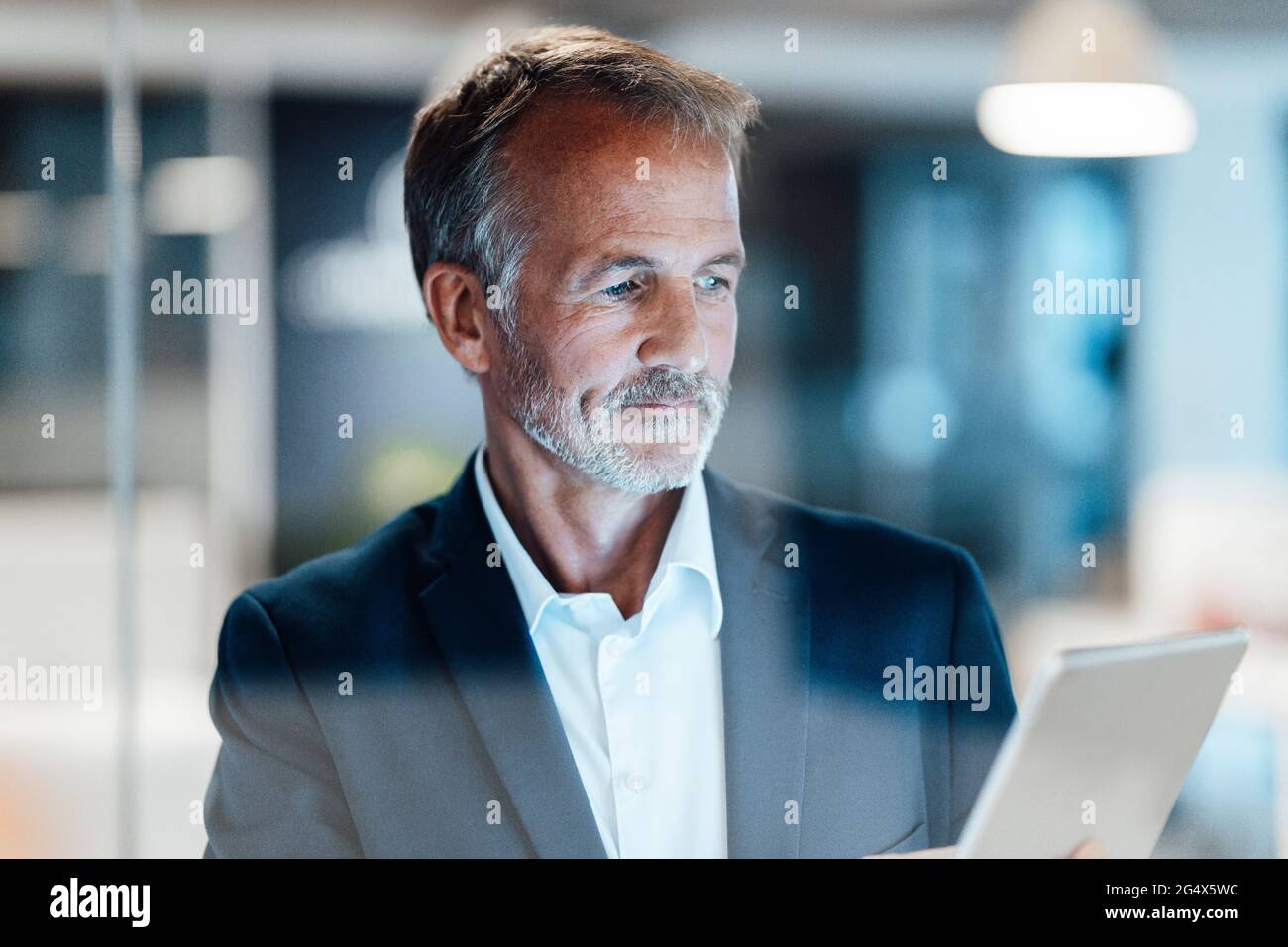 Leitender männlicher Unternehmer, der im Büro ein digitales Tablet verwendet Stockfoto