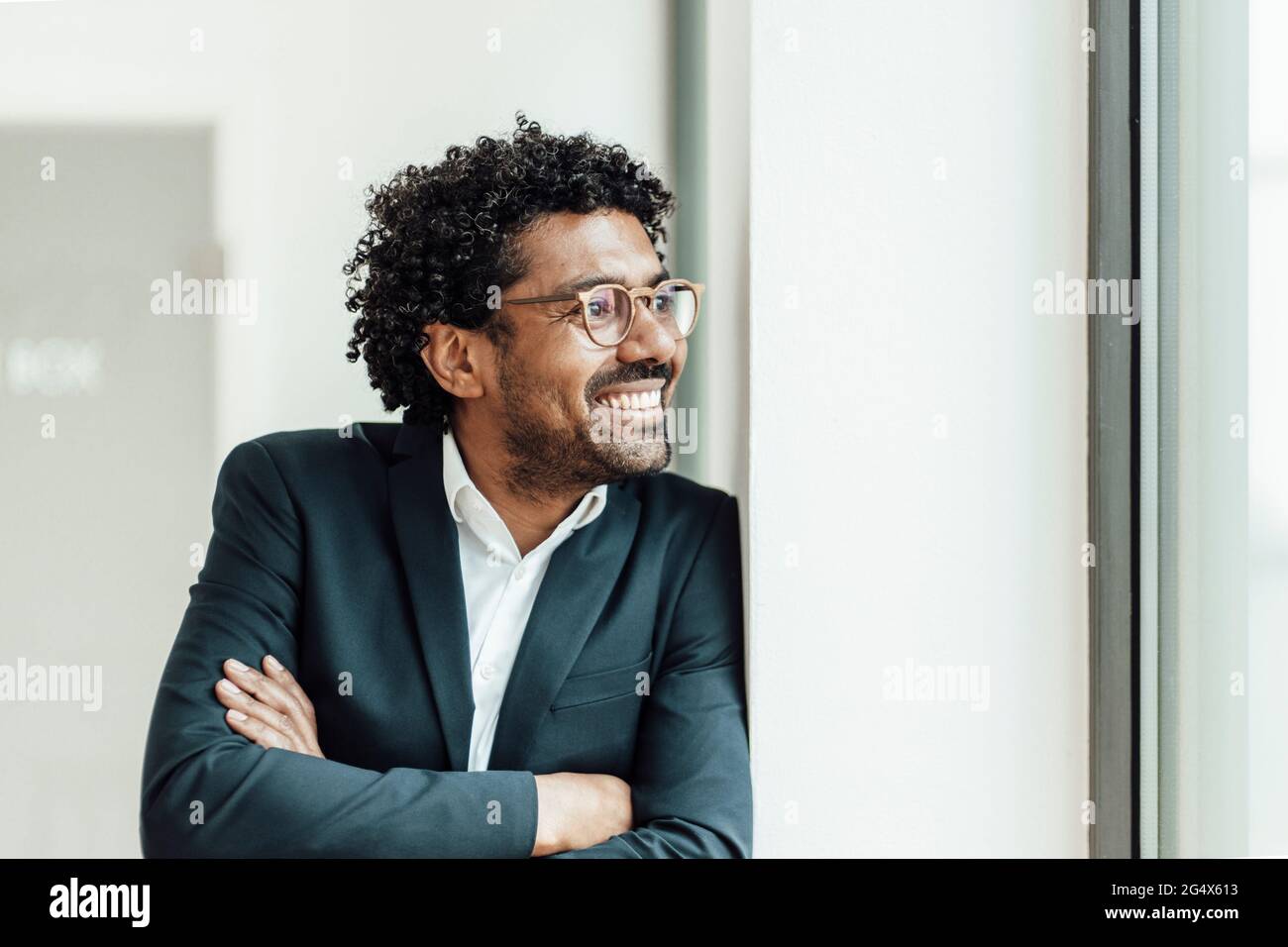 Fröhlicher, reifer Geschäftsmann, der mit gekreuzten Armen dasteht und wegschaut Stockfoto