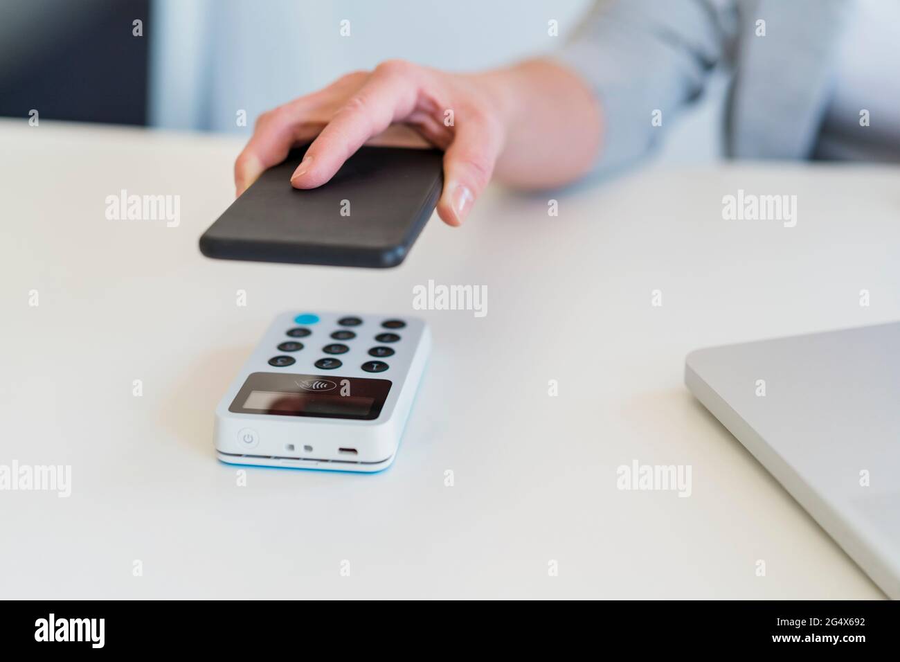 Weibliches professionelles Scan-Mobiltelefon mit Kartenterminal am Schreibtisch Stockfoto