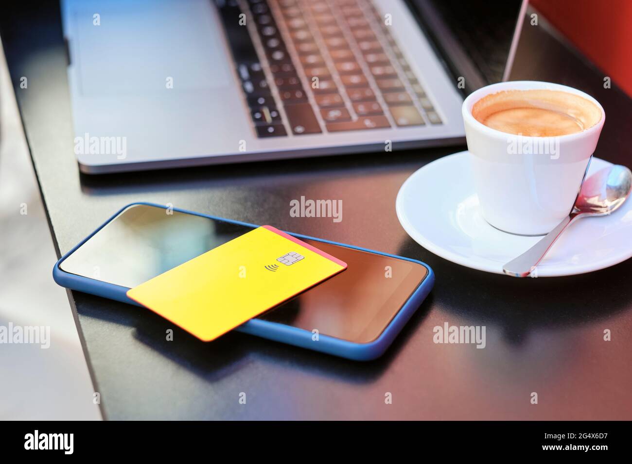 Kreditkarte über Smartphone mit Kaffeetasse und Laptop im Straßencafé Stockfoto