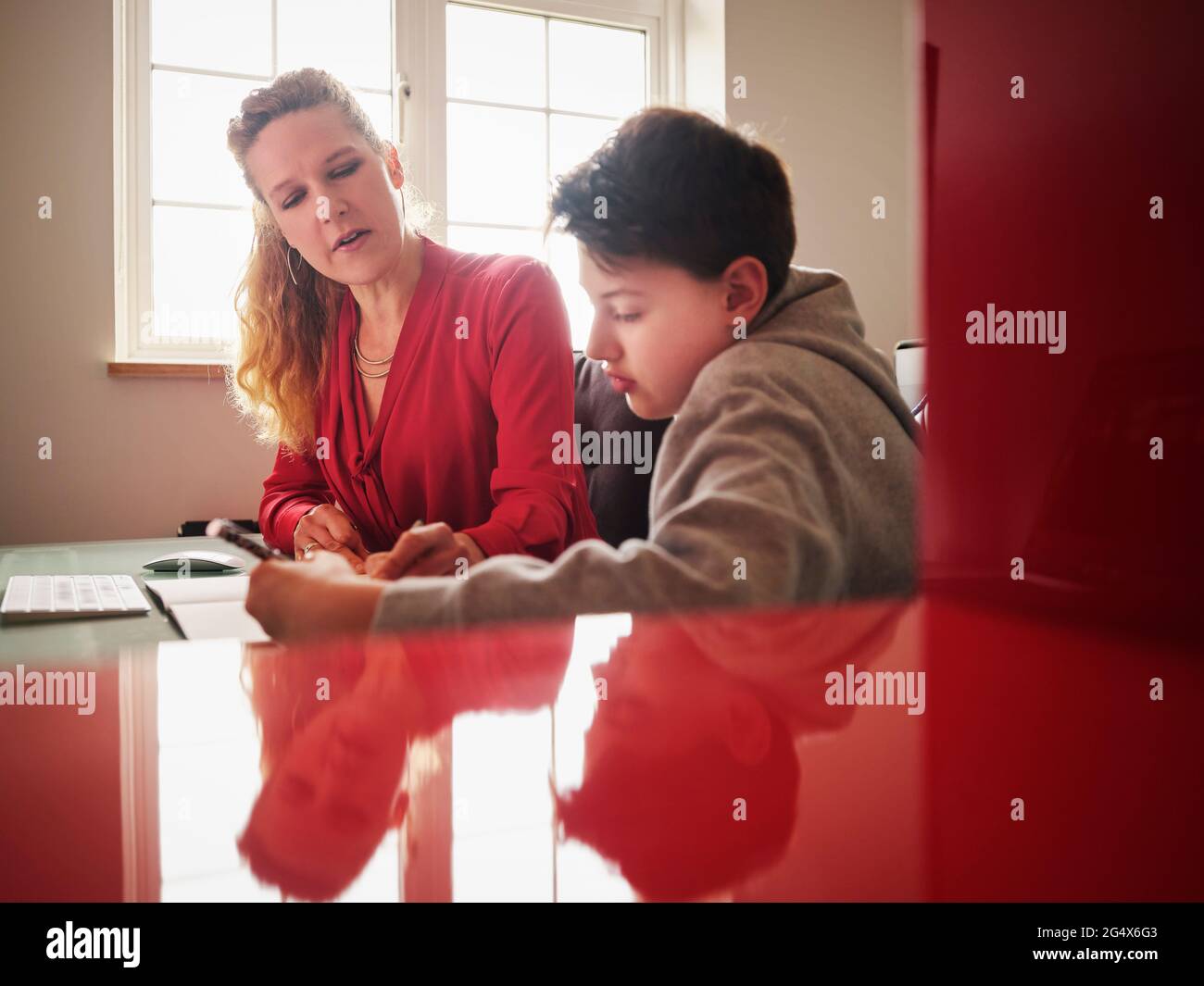 Seriöser Sohn mit Mutter, der zu Hause studiert Stockfoto