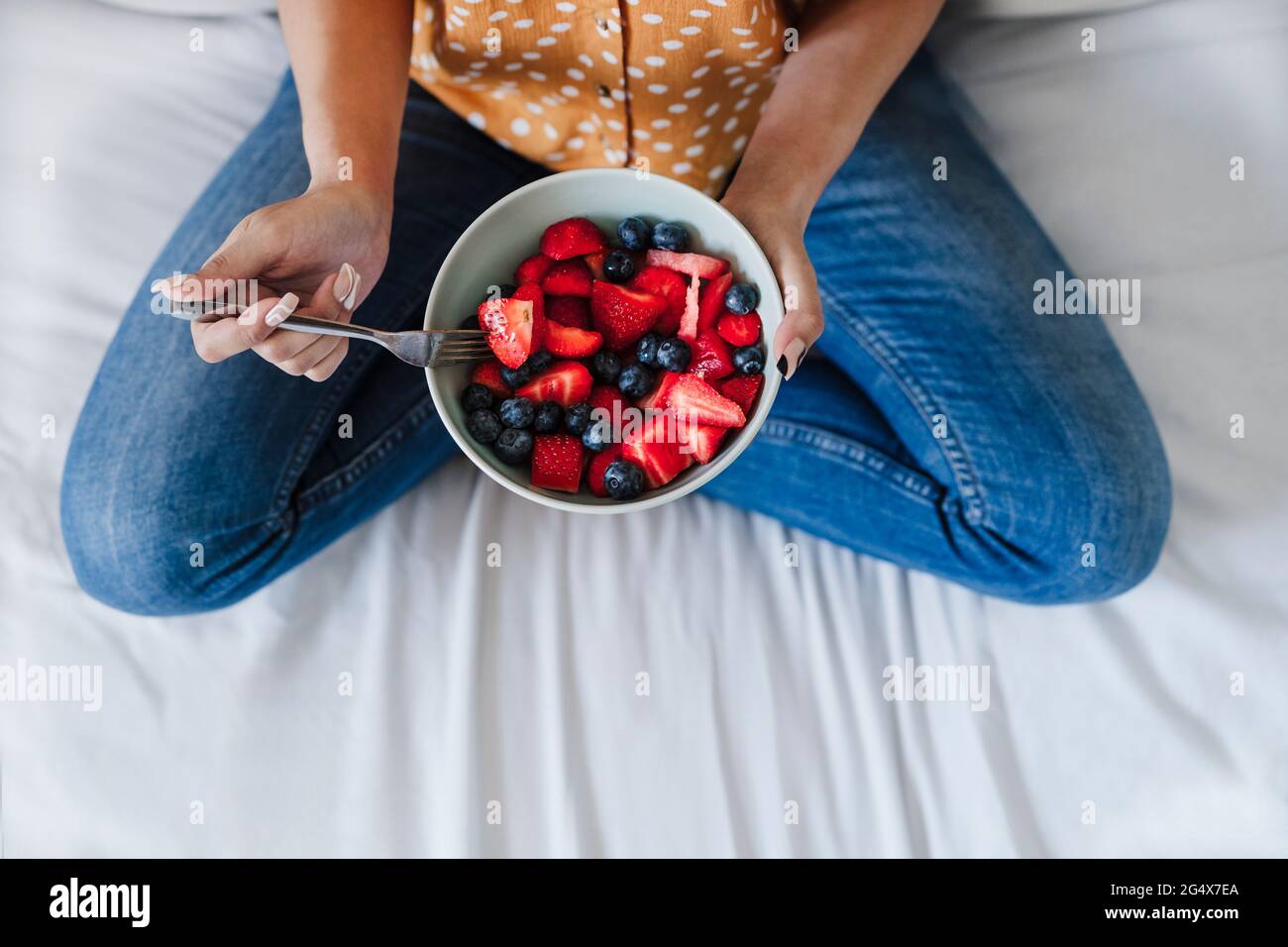 Frau mit frischen Beeren auf dem Bett zu Hause Stockfoto