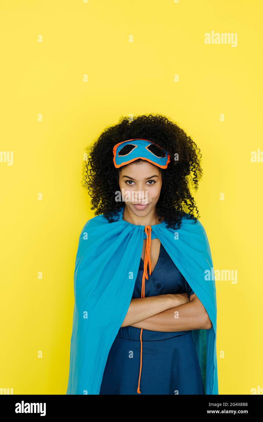 Afro-Frau im Superhelden-Kostüm, das vor gelbem Hintergrund steht Stockfoto