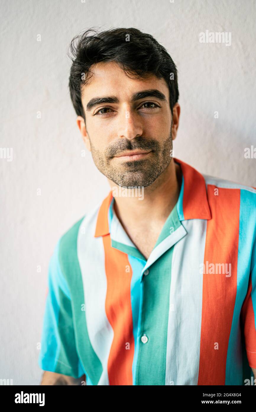 Hübscher Mann, der vor einer weißen Wand steht Stockfoto