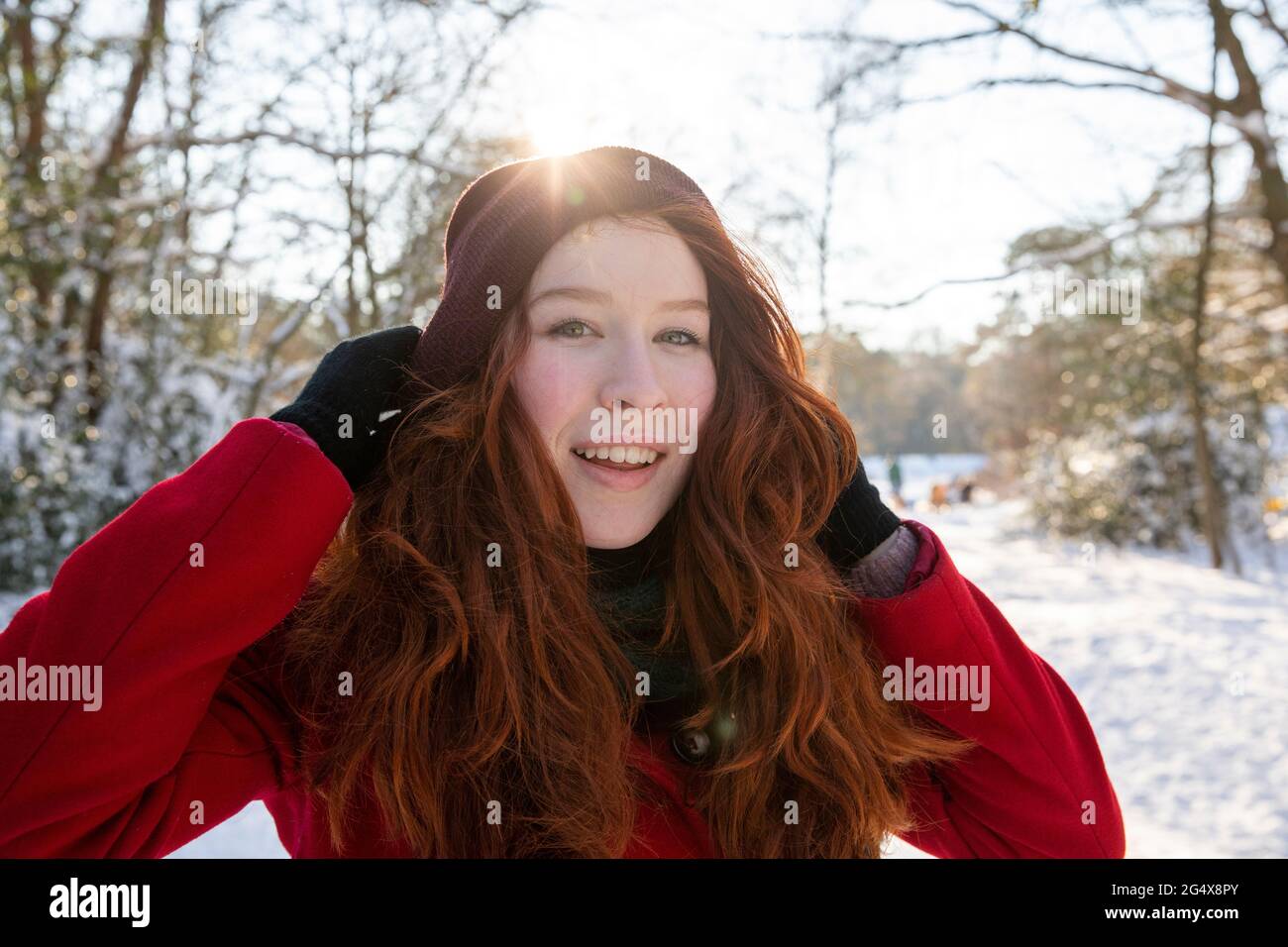Lächelnde Frau mit Händen im Haar im Winter Stockfoto