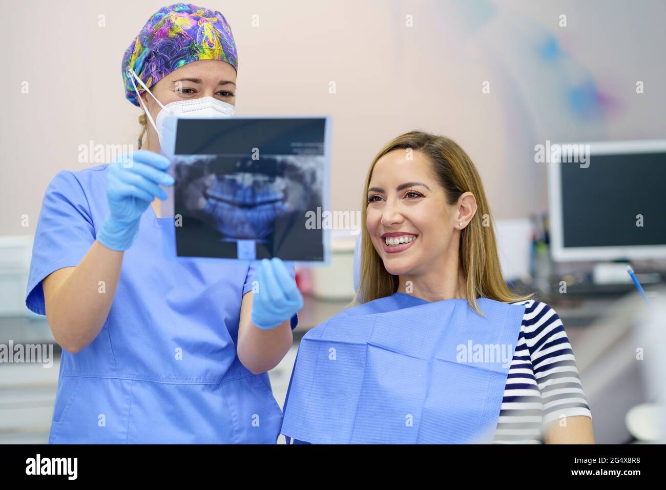 Zahnärztin, die der Patientin in der Klinik Röntgenaufnahmen zeigt Stockfoto