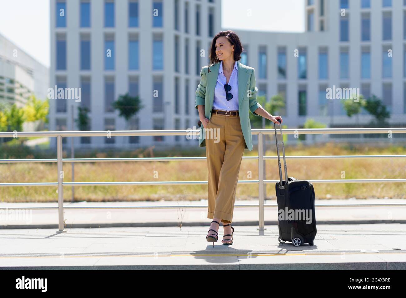 Geschäftsfrau mit Gepäck auf Rädern wartet auf den Zug am Bahnhof Stockfoto