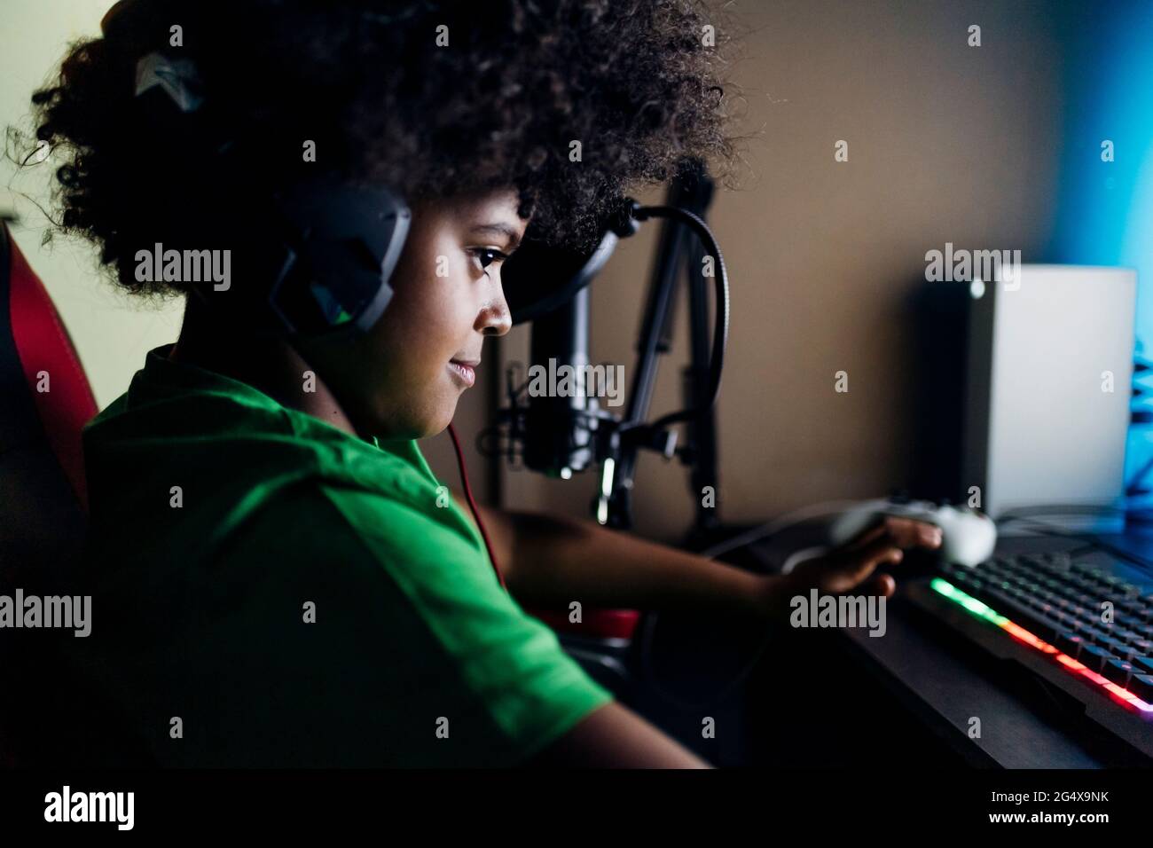 Kleiner Junge mit Kopfhörern, der zu Hause Videospiele spielt Stockfoto