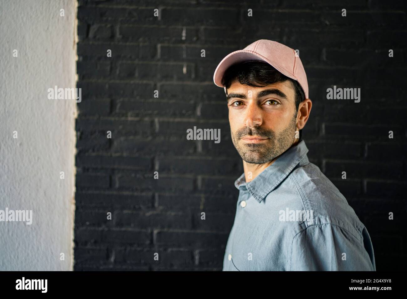 Hübscher Mann, der an der Wand steht Stockfoto