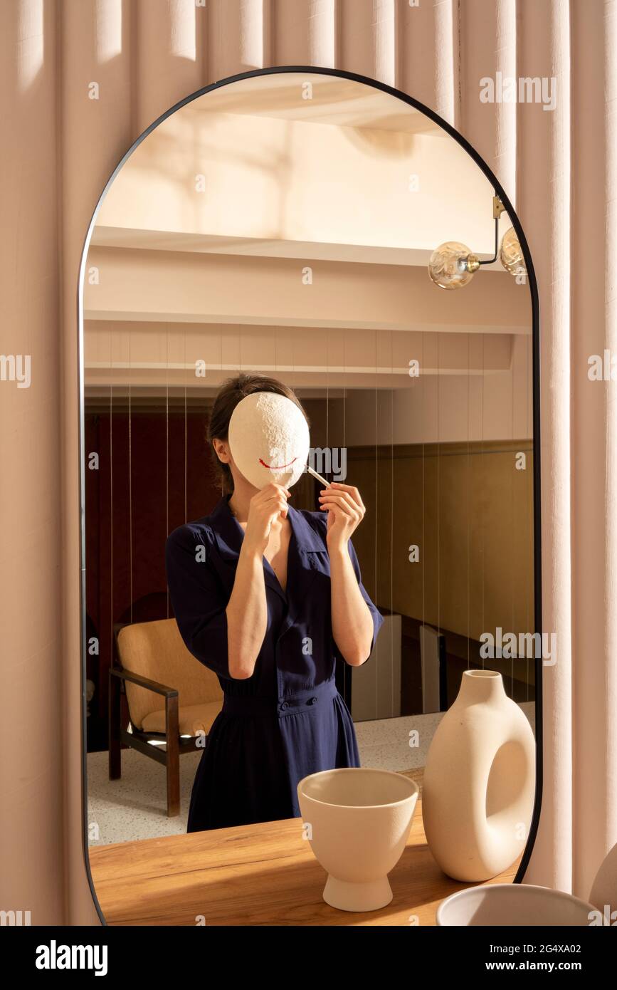 Spiegelung der Frau, die Lippenstift auf weiße Maske anwendet Stockfoto