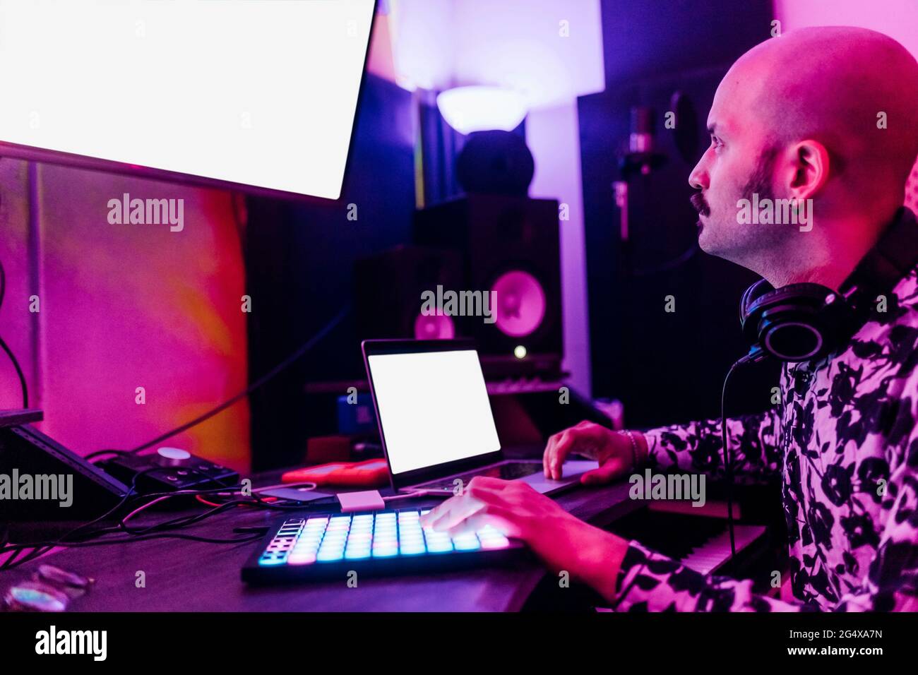 Männlicher Komponist, der beim Komponieren von Musik im Heimstudio auf den Bildschirm des Geräts schaut Stockfoto
