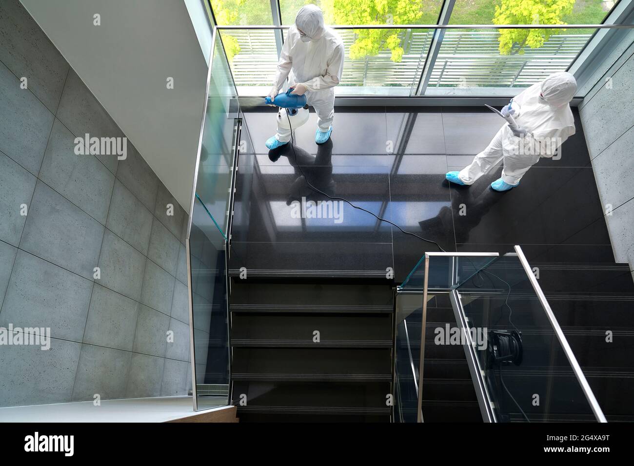 Sanitäre Mitarbeiter desinfizieren die Treppe im Büro Stockfoto