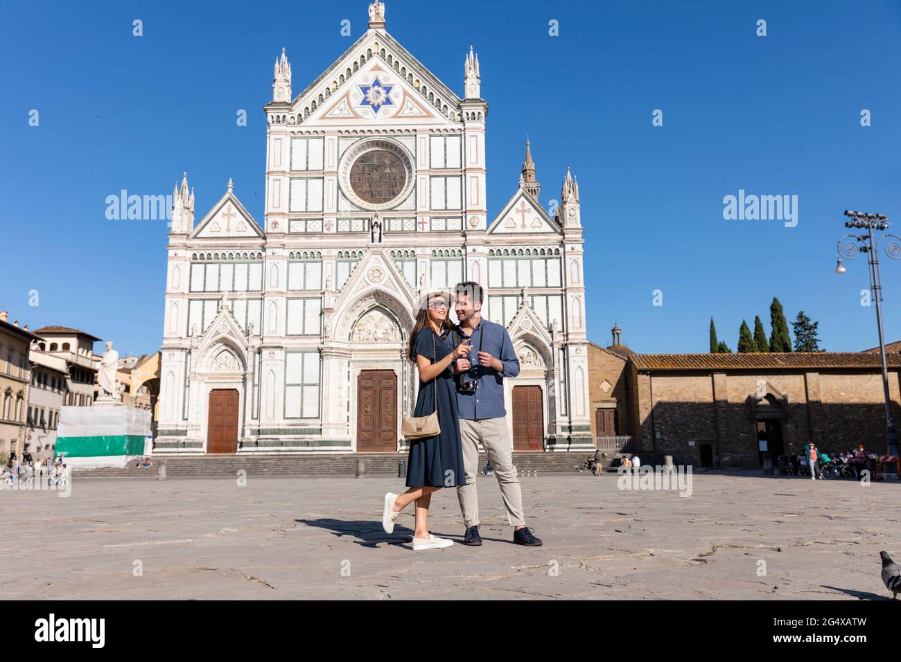 Weibliche Touristen zeigen, während sie mit einem Mann auf der Piazza Di Santa Croce, Florenz, Italien, stehen Stockfoto