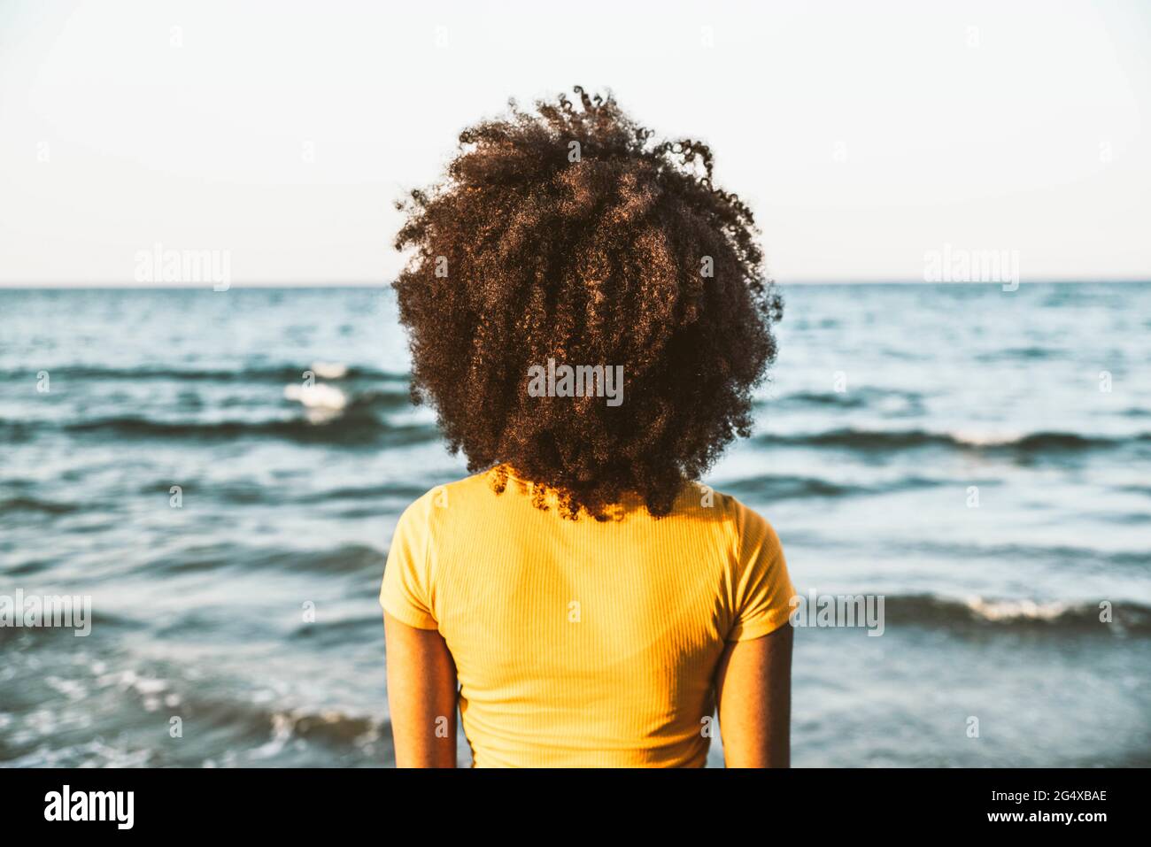 Afro-Frau, die am sonnigen Tag vom Strand aus auf den Horizont blickt Stockfoto