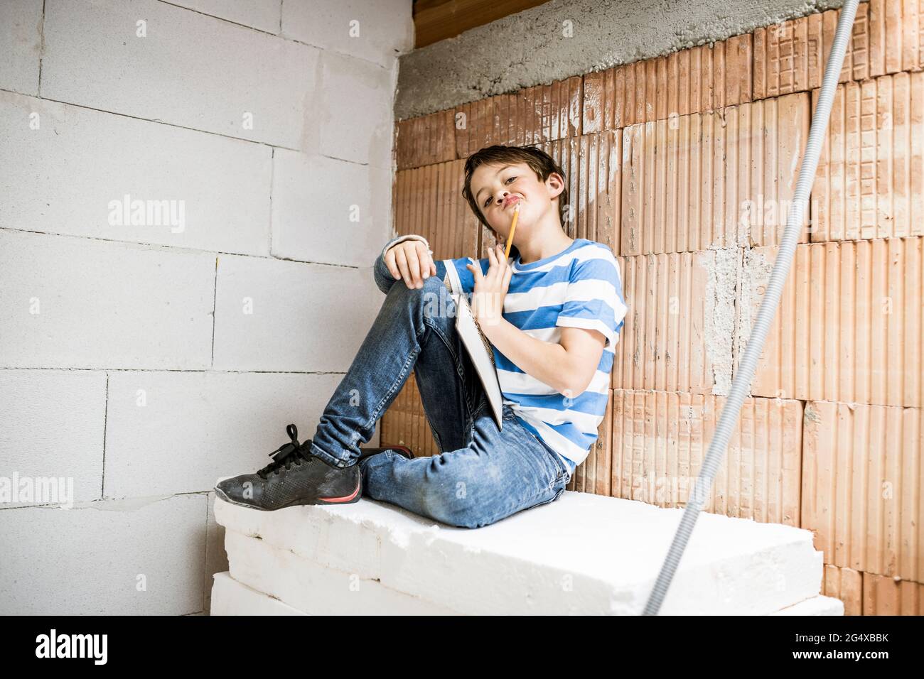 Junge, der beim Wiederaufbau des Hauses auf Block sitzt Stockfoto
