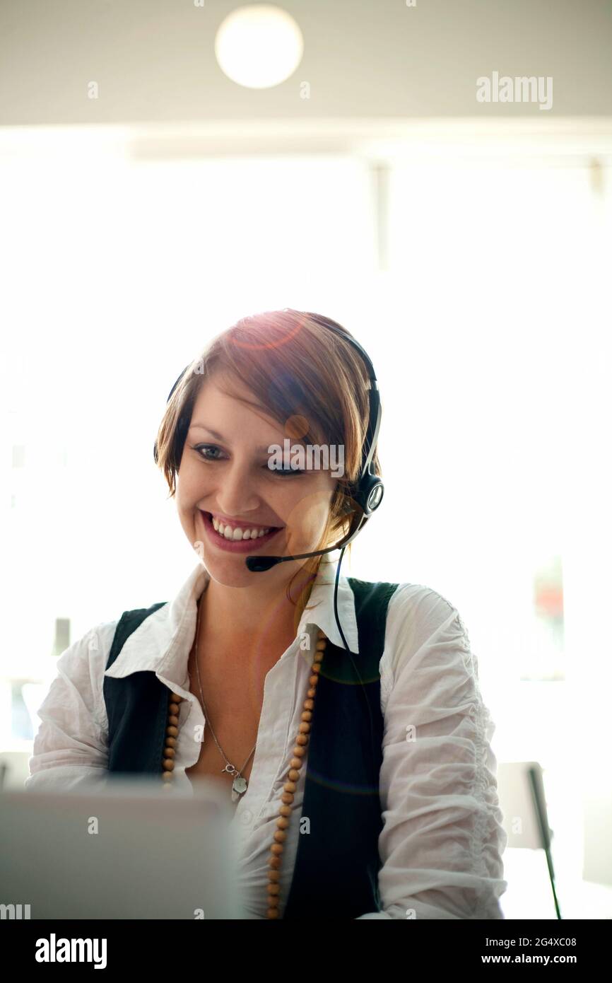 Lächelnde Geschäftsfrau mit Headset während eines Videoanrufs auf dem Laptop im Café Stockfoto