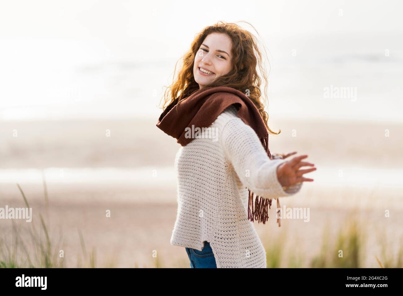 Glückliche Frau mit ausgestreckten Armen, die am Strand steht Stockfoto