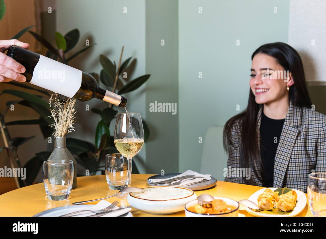 Der männliche Kellner serviert Getränke in Weinglas von einer lächelnden Geschäftsfrau im Restaurant Stockfoto