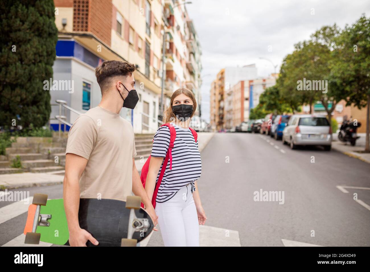 Paar in schützender Gesichtsmaske überqueren Straße in der Stadt während COVID-19 Ausbruch Stockfoto
