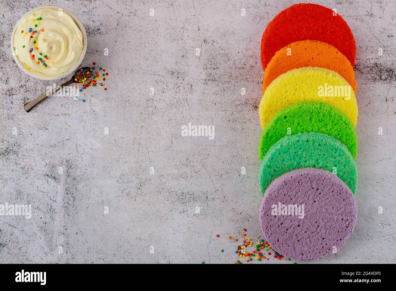 Weiße Glasur in Schüssel mit rundem Biskuitkuchen. Stockfoto