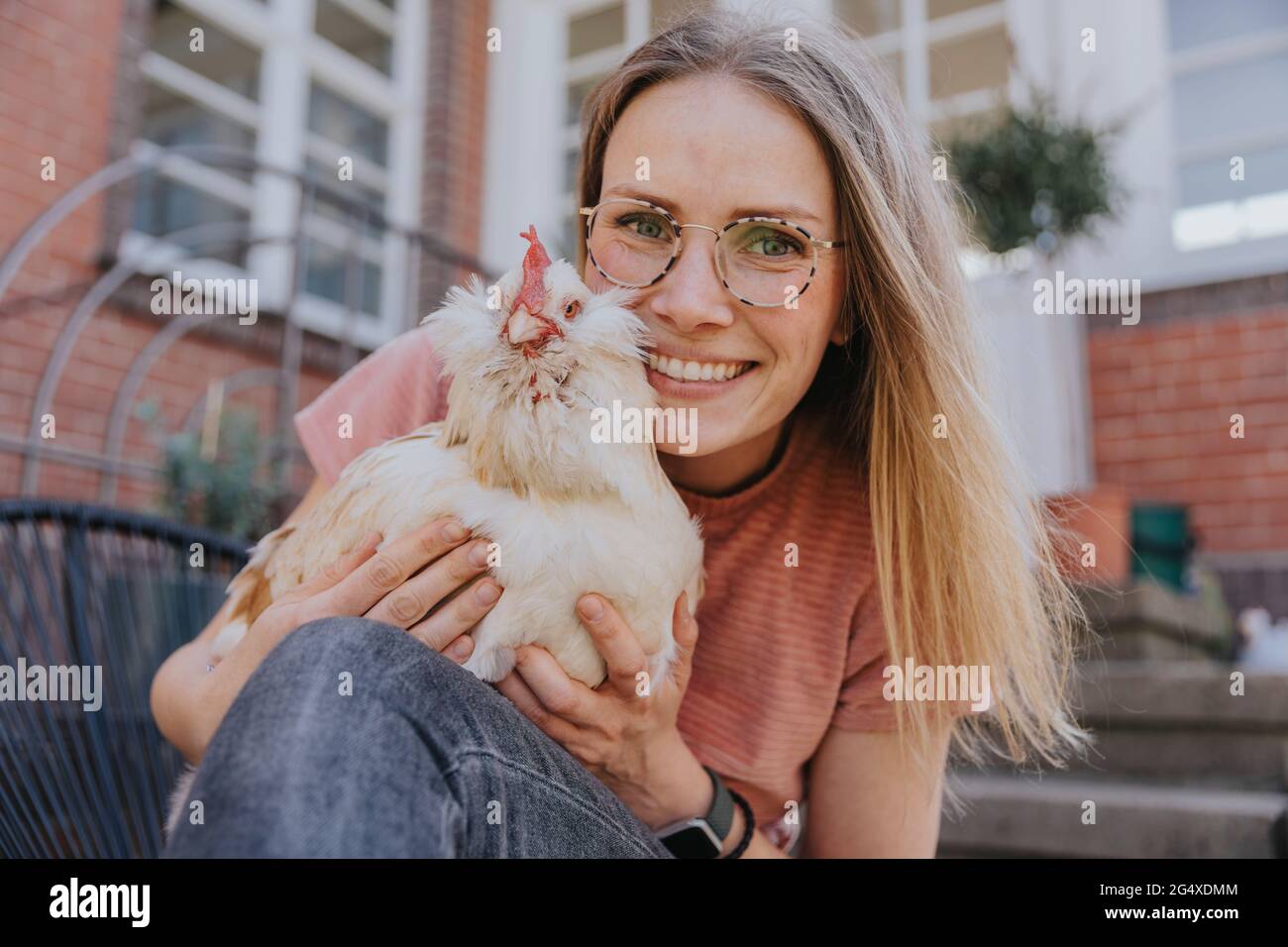 Lächelnde Frau mit Huhn im Hinterhof Stockfoto