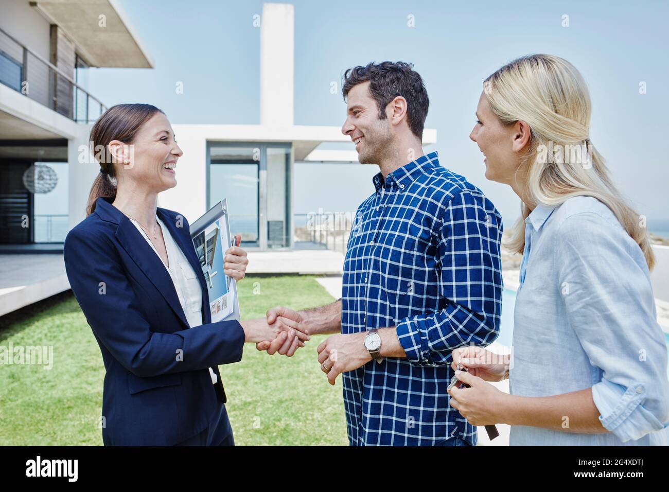 Kunden tun Handshake mit Immobilienmakler auf Rasen Stockfoto