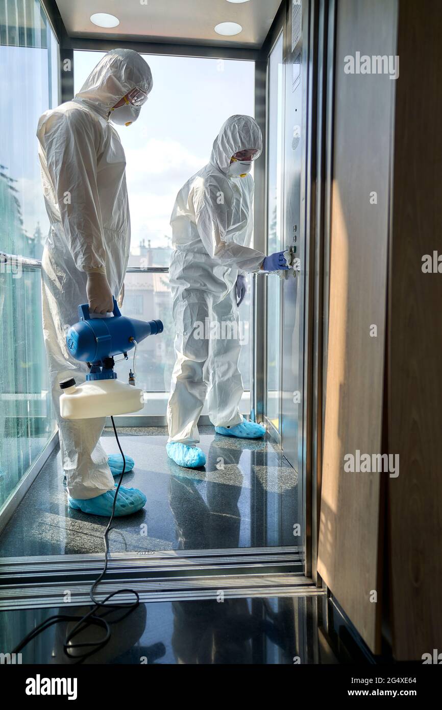 Sanitäre Mitarbeiter desinfizieren den Büroaufzug Stockfoto