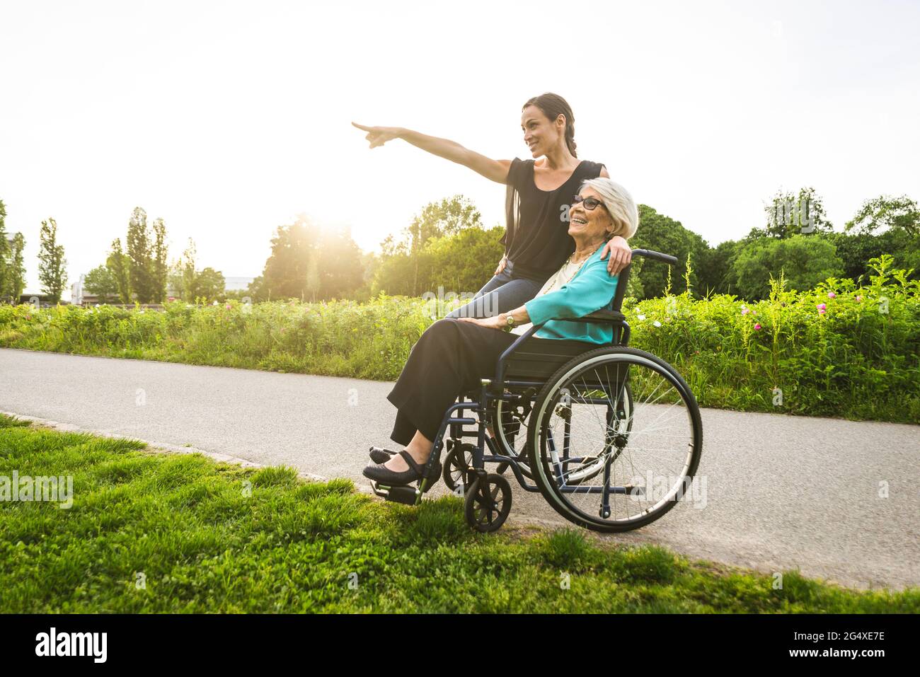 Enkelin zeigt mit Großmutter, die im Rollstuhl im Park sitzt Stockfoto