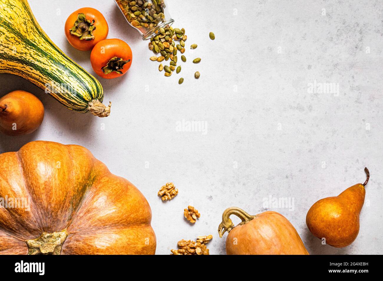 Herbstlicher Hintergrund mit Kürbissen, Birnen, Walnüssen, Kürbiskernen, Kaki und Kopierraum Stockfoto