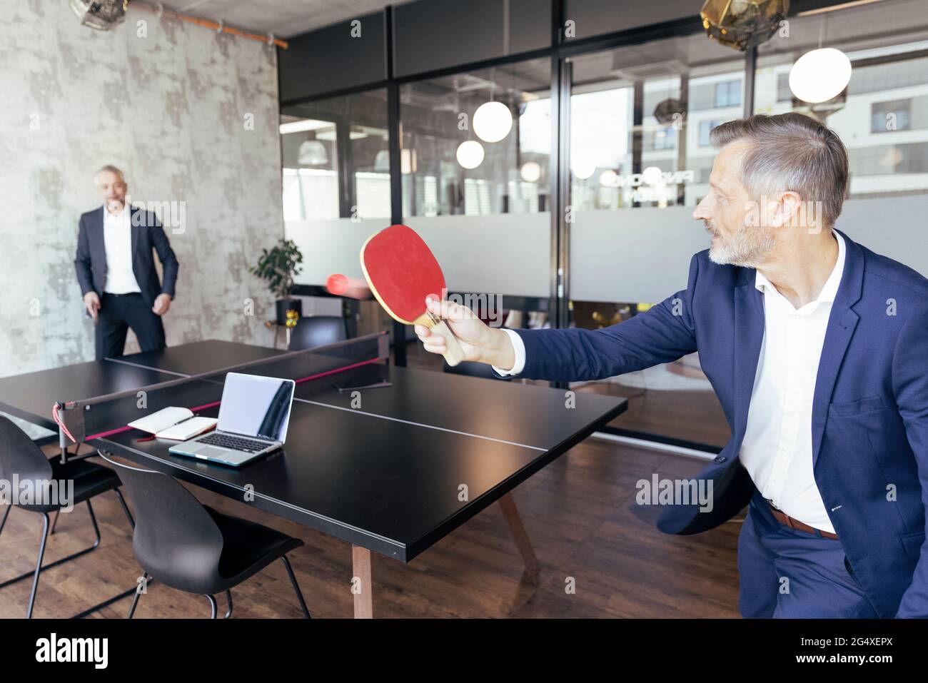 Männliche Profis spielen Tischtennis im Büro Stockfoto